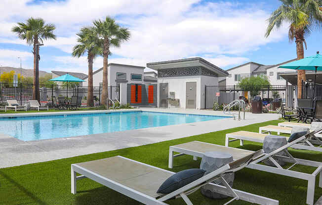 a swimming pool with lounge chairs and palm trees