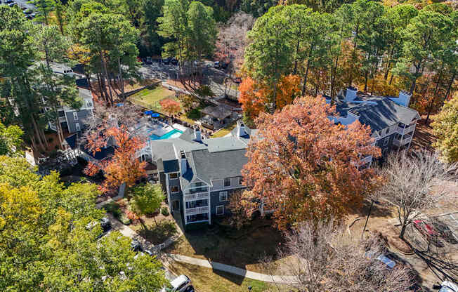 An aerial view of a house surrounded by trees in autumn.