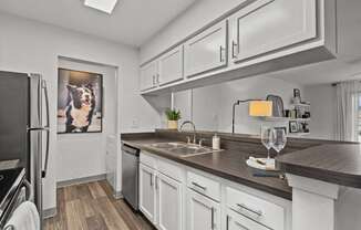 A modern kitchen with white cabinets and a wooden countertop.