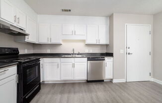 A kitchen with white cabinets and black appliances.