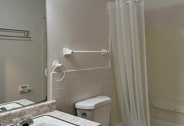A white toilet sits next to a sink in a bathroom.