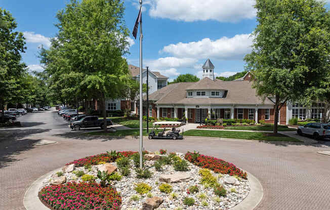 a flag pole in the middle of a flower garden in front of a house
