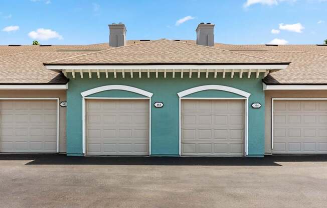 A two-car garage with white doors is attached to a house with a brown roof.