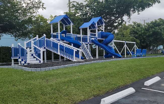 a playground with a blue set of slides in a parking lot