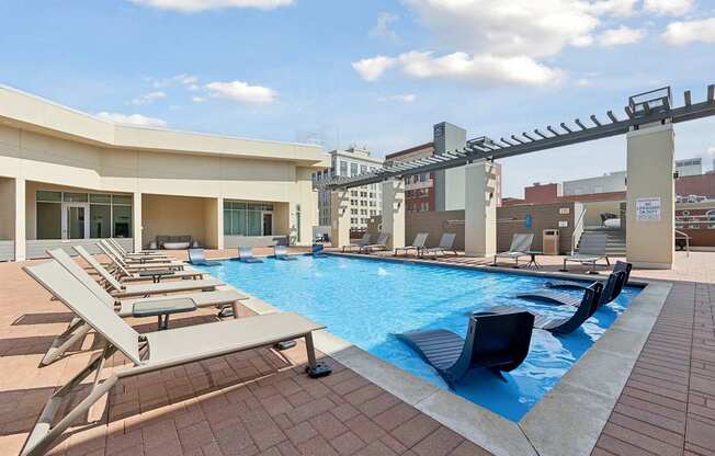 Rooftop pool with sun loungers and a building in the background.