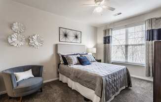 Eagle Creek, IN Apartments Near Downtown Indianapolis - Riverchase - Spacious Bedroom With Carpet Flooring, A Ceiling Fan, And A Window With Blinds
