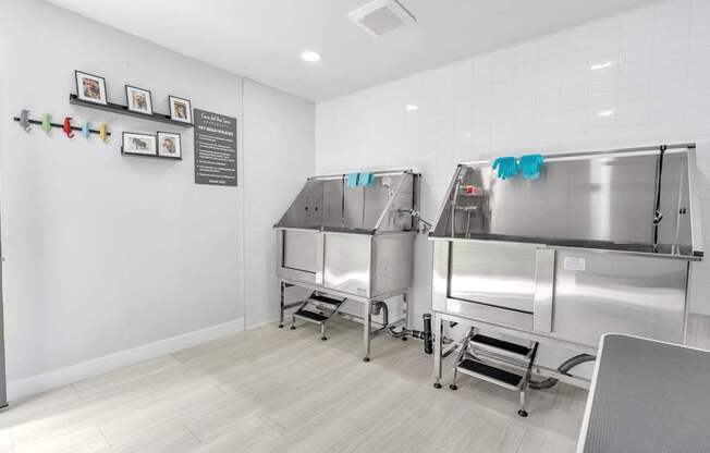 A clean, empty commercial kitchen with stainless steel appliances and white walls.