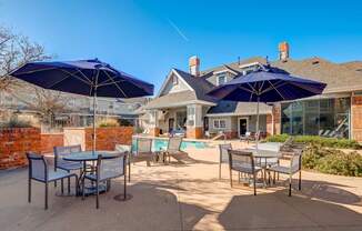 patio with tables and chairs and umbrellas in front of a house