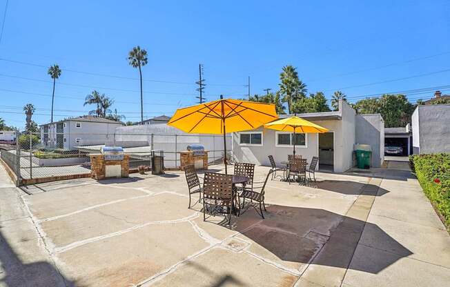 A patio with a yellow umbrella and chairs.