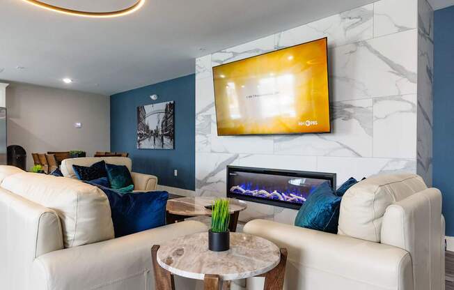 A living room with a white couch, a coffee table, and a flat screen TV mounted on the wall.