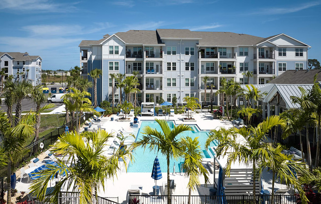 a large pool with palm trees in front of an apartment building