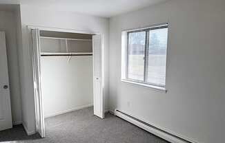 A spacious bedroom with a large closet and a window at Waverly Park Apartments, Lansing