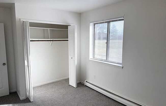 A spacious bedroom with a large closet and a window at Waverly Park Apartments, Lansing