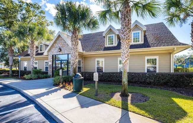 A house with a driveway and palm trees in front.