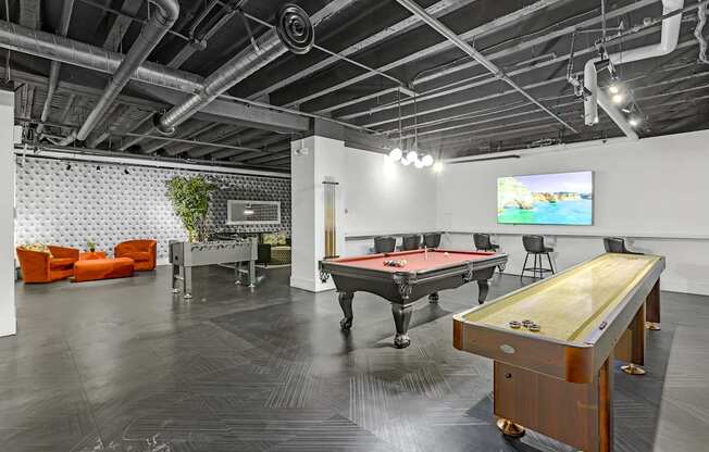 A pool table is in the middle of a room with a TV on the wall.