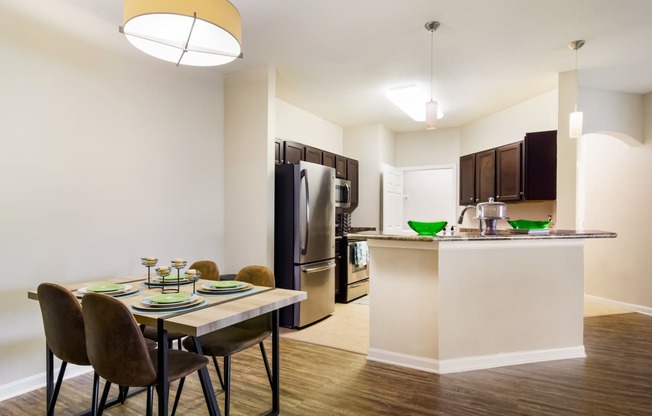 a dining area with a table and chairs and a kitchen in the background