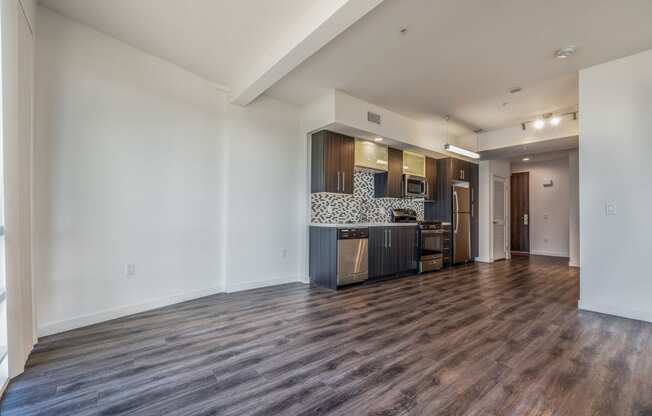 a living room and kitchen with a wood floor and white walls