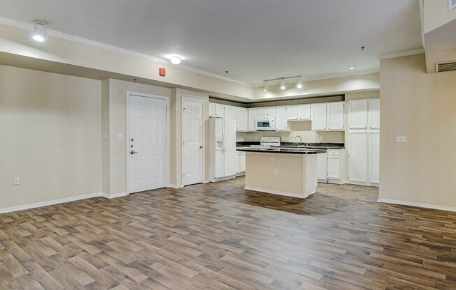 an empty living room and kitchen with a counter top in the middle