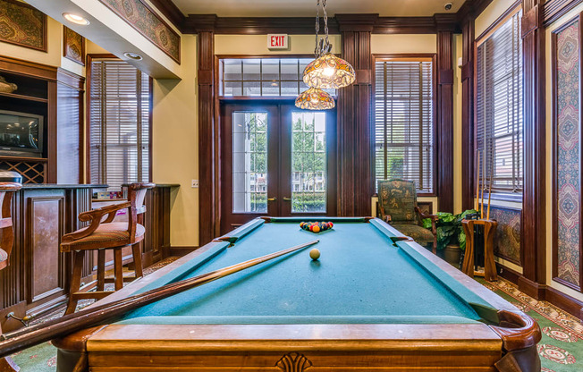 A pool table in a room with a view of the outside.