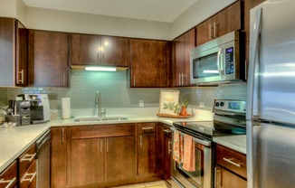 a kitchen with wooden cabinets and stainless steel appliances at Central Park East in Arlington Heights, IL