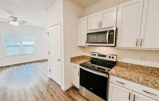 a kitchen with white cabinets and a stove and a microwave