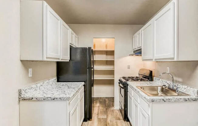 a kitchen with white cabinets and a black refrigerator at Gates of West Bay, Norfolk Virginia