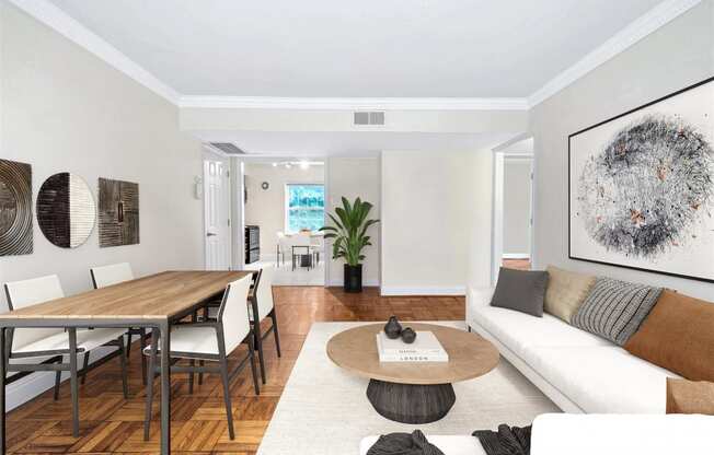 an open living room and dining room with white furniture and a wooden table