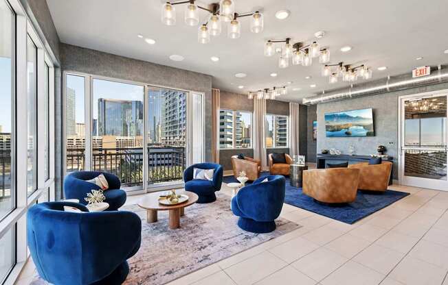 A spacious living room with blue chairs and a view of the city.