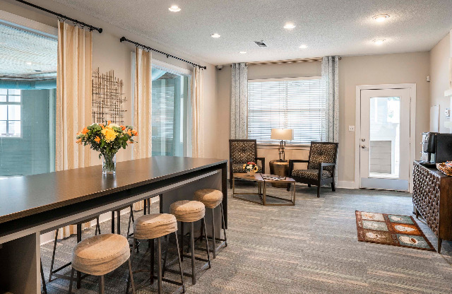 Lounge at our apartments in Nashville, featuring carpeted flooring, counter seating, and cushioned chairs.