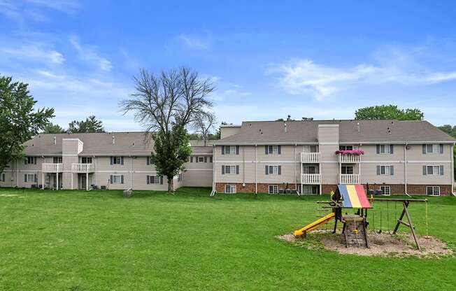 a field of green grass and playground outside sun valley apartments