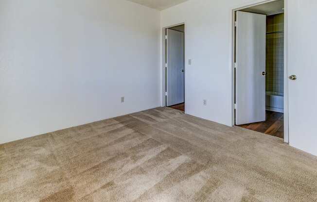 a bedroom with a carpet and a door to a bathroom