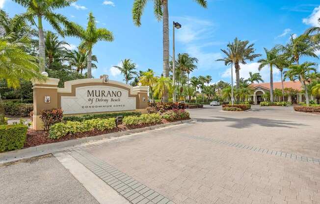 The entrance to the Murano Condominium Homes is surrounded by palm trees.