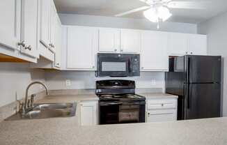 a kitchen with white cabinets and black appliances