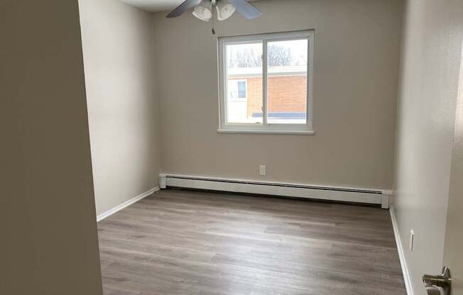 A room with a ceiling fan and a window.