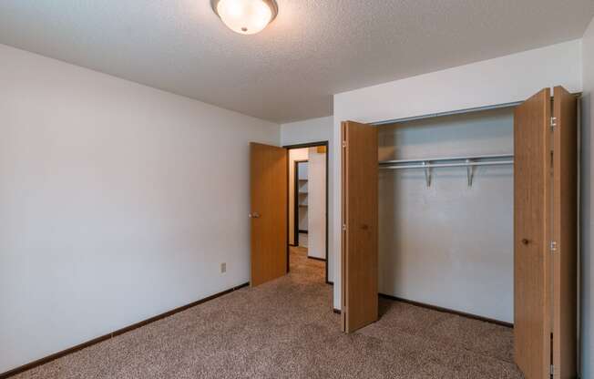 An empty bedroom with a closet and a mirrored closet door. Fargo, ND Long Island Apartments.