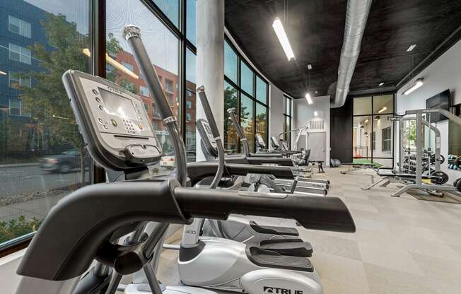 a gym with weights and exercise equipment in a building with large windows