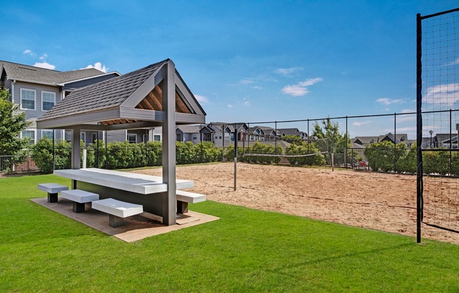 a picnic area with a picnic table and benches next to a volleyball court