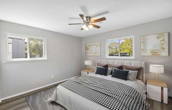 A bedroom with a bed, two lamps, and two paintings on the wall.