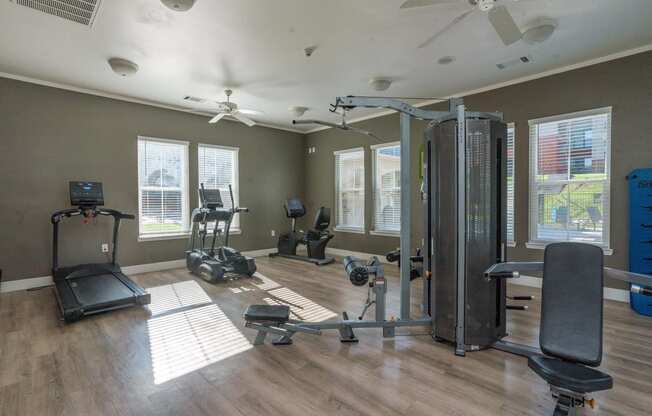 a gym with exercise equipment and windows in a home with wood floors