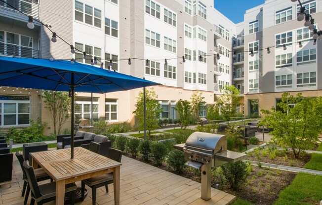 a patio with an umbrella and a table with chairs and a grill