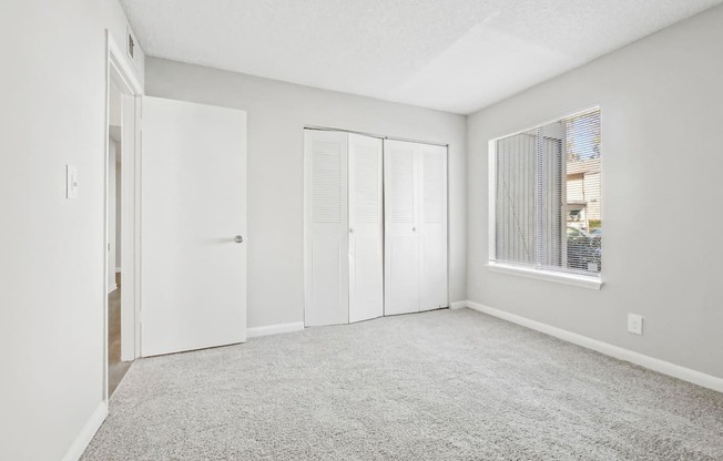 Second bedroom with carpeted floor and sliding doors closet on the side in B1 floor plan at Riverwood Crossing apartments in Roswell, GA..