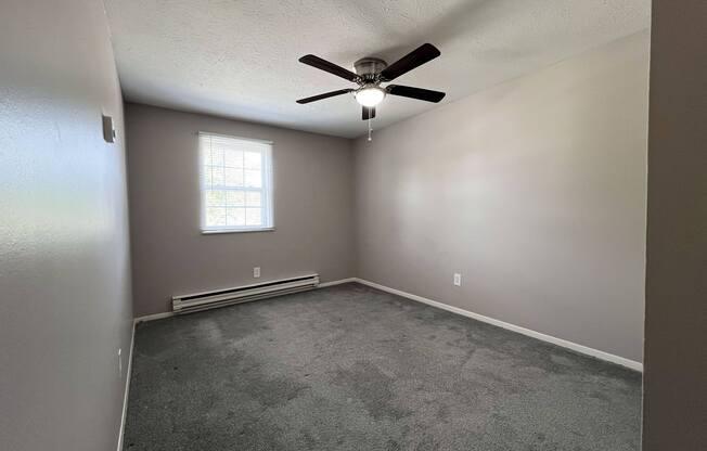 an empty room with a ceiling fan and a window