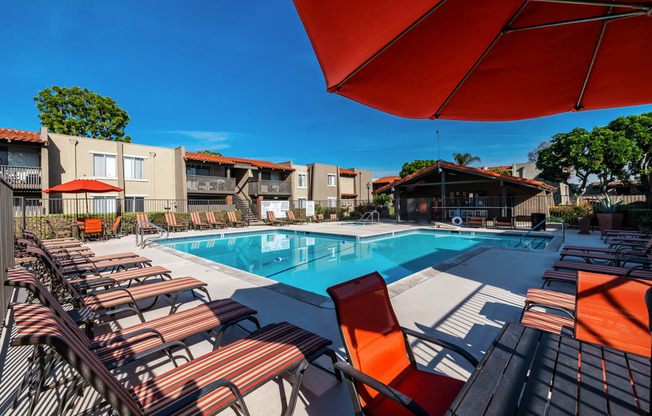 a pool with chairs and an umbrella next to a swimming pool