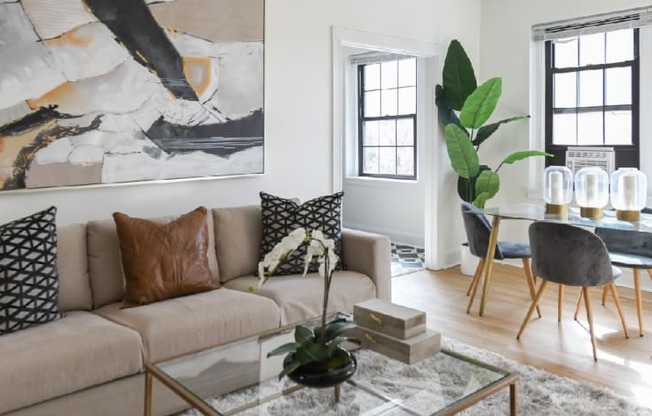 living area with large windows, sofa, coffee table, hardwood floors and view of dining area at the dahlia apartments in washington dc