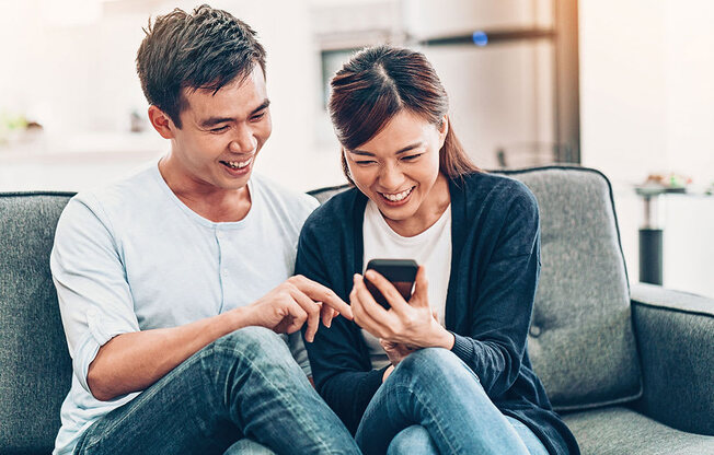 a man and woman sitting on a couch looking at a cell phone at Brownstones at Palisade Park Townhomes, Colorado