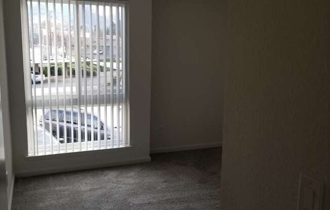 A car is parked outside a window with blinds.