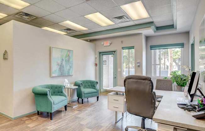 A room with a desk, chairs, and a painting on the wall.