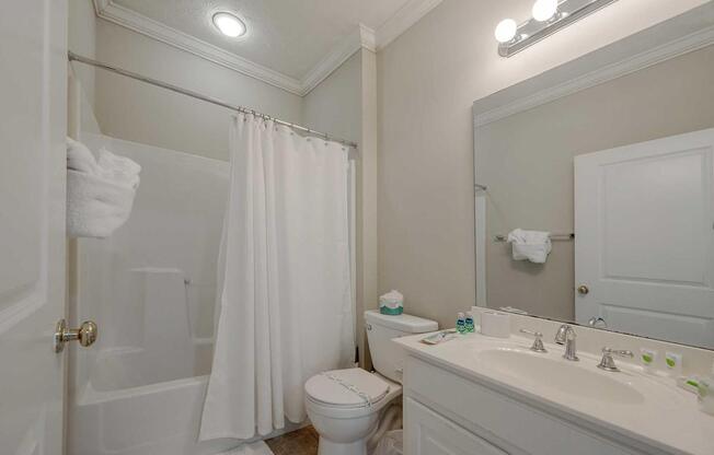 A white bathroom with a toilet, sink, and shower.