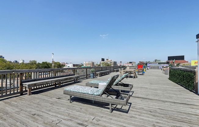 A wooden boardwalk with benches and a view of the city in the distance.
