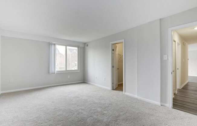 an empty living room with a door to a hallway and a window